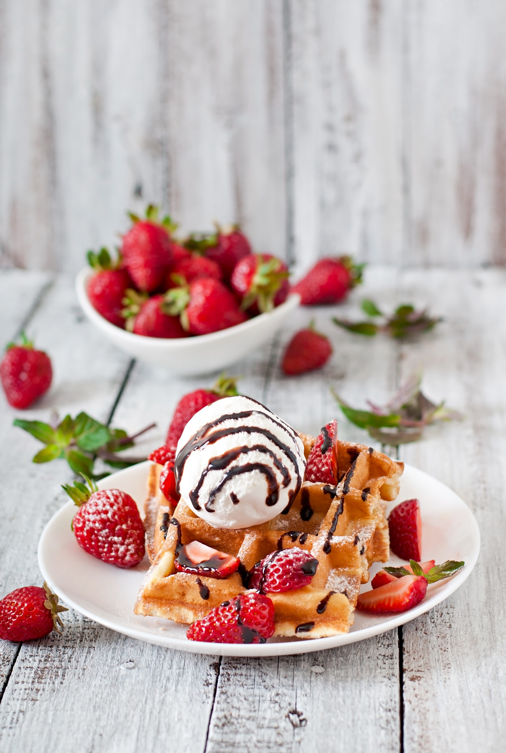 Belgium waffles with strawberries and ice cream on white plate